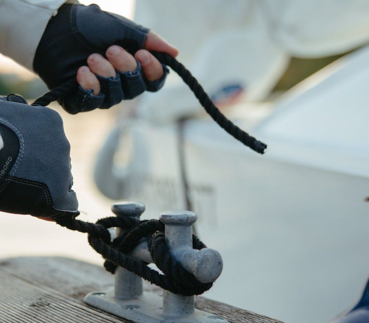 Hands tying a dock line on a yacht cleat